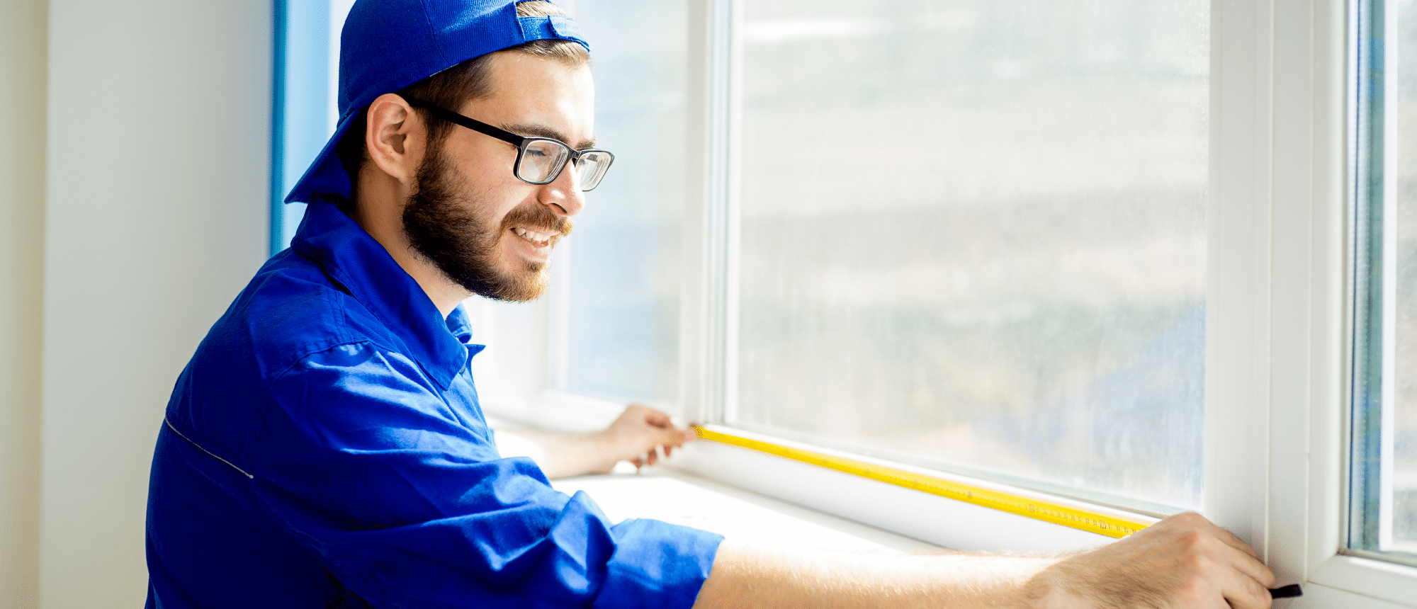 Man in blue measures window